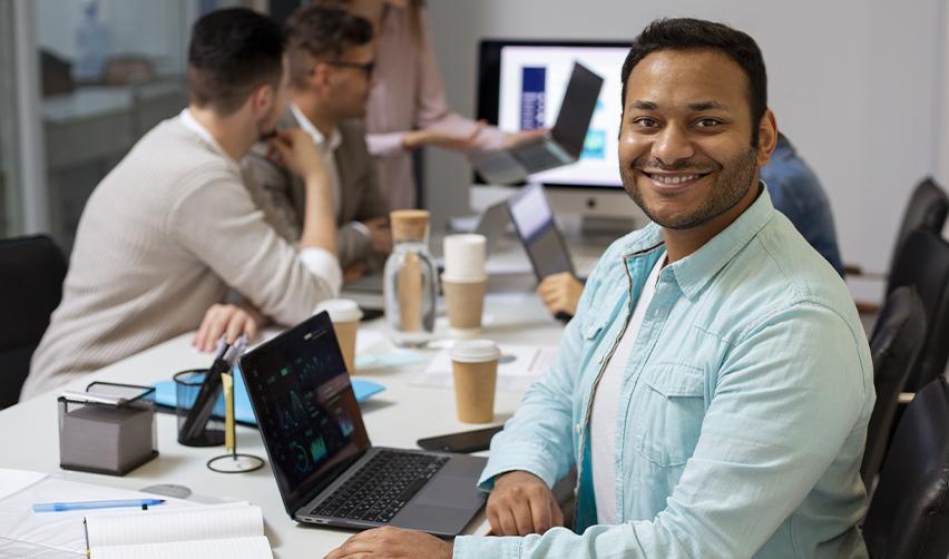 An Indian employment based green card holder sitting at an office desk, smiling at the camera.