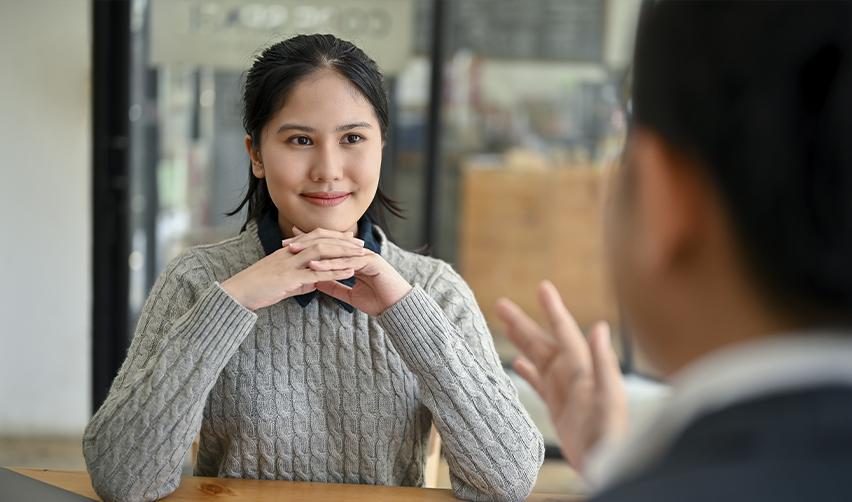 A green card holder sitting at a table with her hands folded, listening to an EB-5 immigration attorney about employment based visas.
