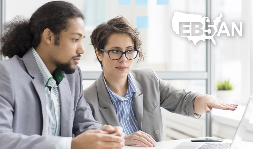 Two people looking at a computer screen and discussing immigrant visas or the U.S. immigration process, with the EB5AN logo on the side.