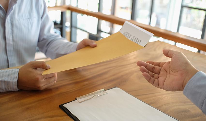 A person handing an envelope to another person with source of funds and job creation documents in it.