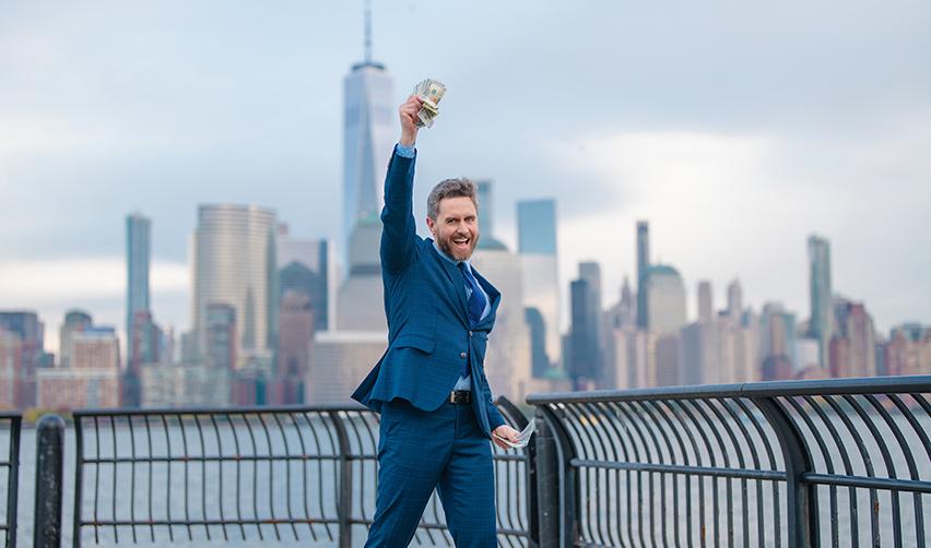 A happy U.S. permanent resident holding up a stack of money, celebrating the success of his own business.