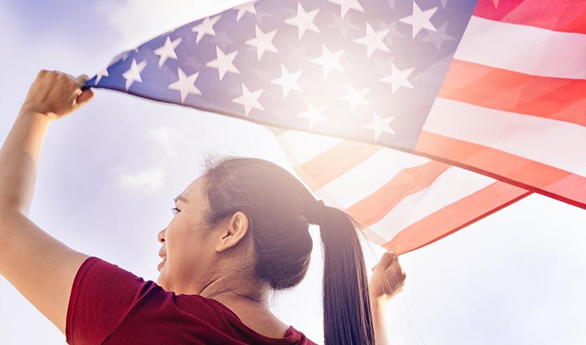 A lawful permanent resident holding the American flag up to the sky.
