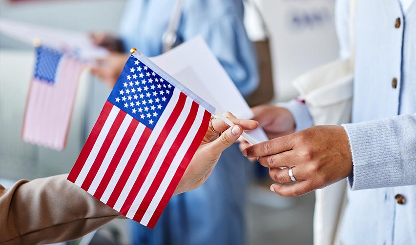 Two people holding a U.S. flag, symbolizing unity, safety, and government sponsored financial aid for permanent resident card holders.