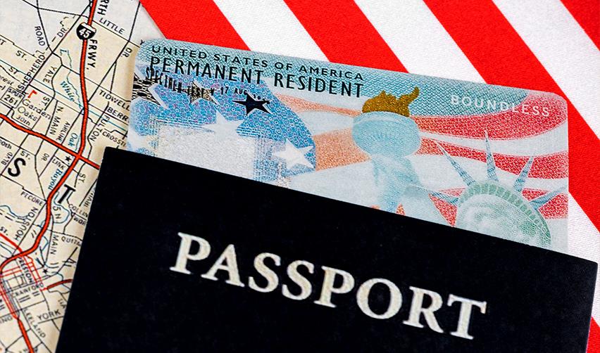 A valid green card inside a passport on a flag and a map, symbolizing the benefits of green card.