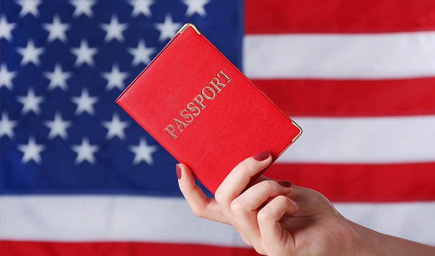 A US citizen holding a passport in front of the American flag.