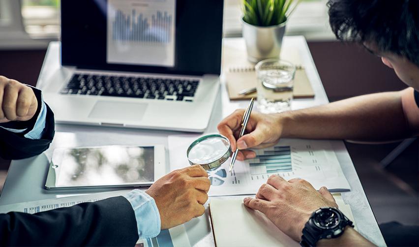 Two people examining some targeted employment area commercial enterprise documents to participate in U.S. Citizenship and Immigration Services EB-5 regional center program.