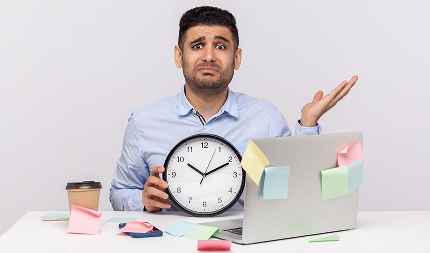 A person holding a clock in front of a computer, symbolizing backlogs in green card for Indians.