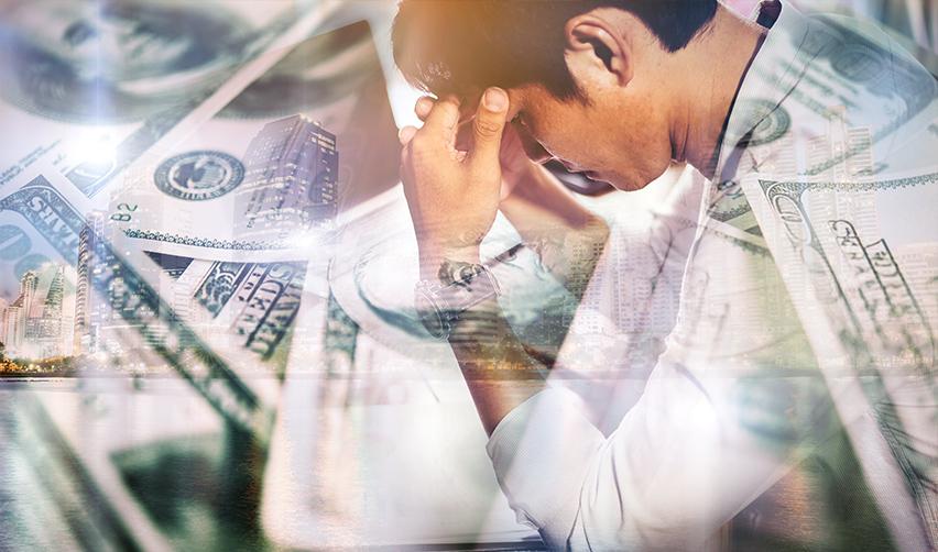 A person holding his head in stress over his immigration status, with overexposed dollars in the foreground.