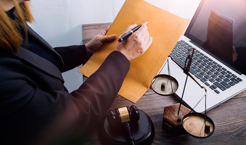 A person writing on an envelope in front of a computer, symbolizing the visa registration process.