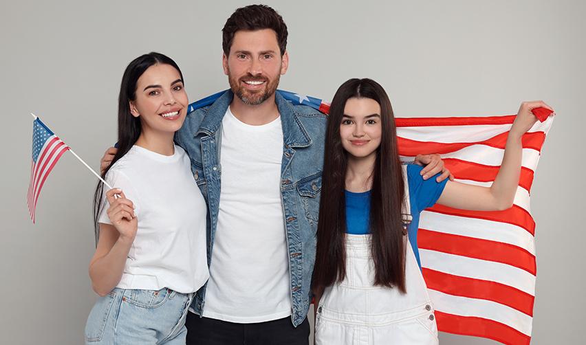 A Canadian Eb-5 immigrant investor family holding up U.S. flags after they obtain permanent residency through regional center investments.
