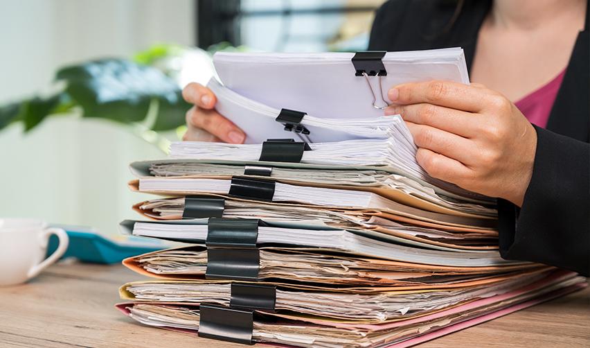 A U.S. Citizenship and Immigration Services officer holding papers a stack of permanent residency documents.