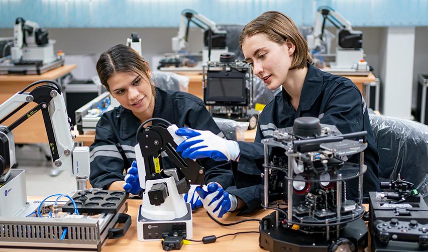 Two STEM students working on a machine, who may pursue an H-1B visa through the electronic registration process.