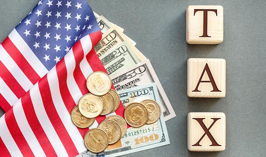 EB-5 capital investment money on top of an American flag and wooden blocks spelling out tax.