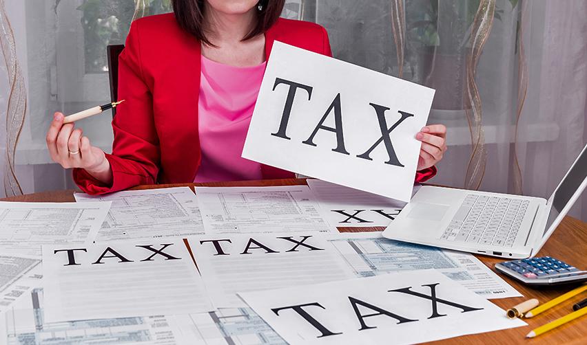 A financial advisor on a desk with documents on it, holding up a piece of paper that reads