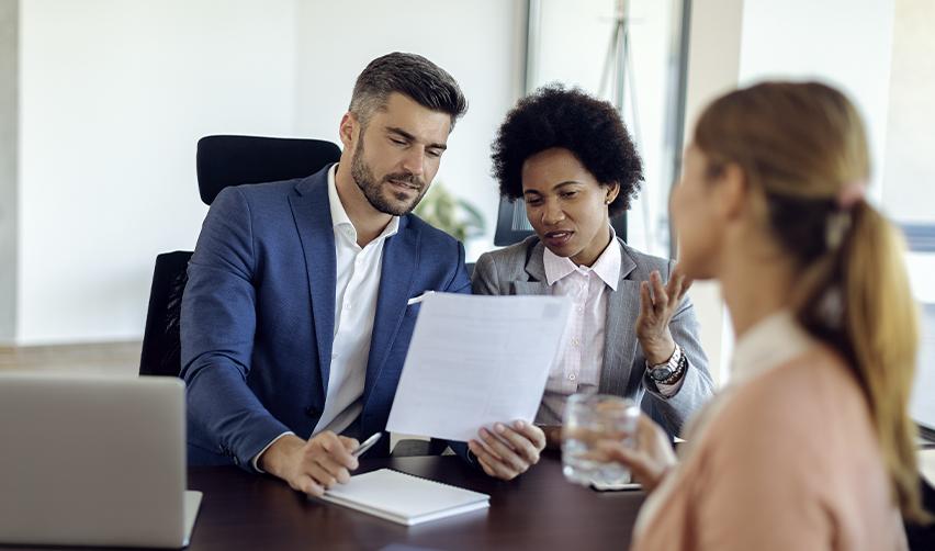 Investors sitting at a desk looking at project documents with the help of an EB-5 expert.