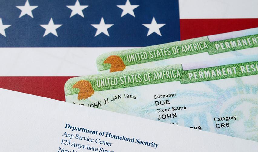 Two green cards showing permanent residence status with a letter from DHS and an American flag in the background.