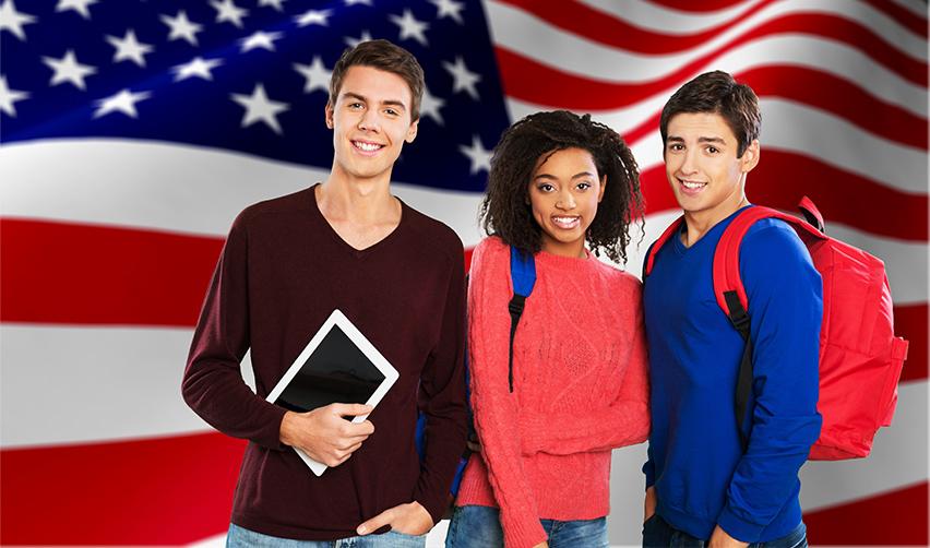 A Green Card holder holding an American flag and giving two thumbs up.