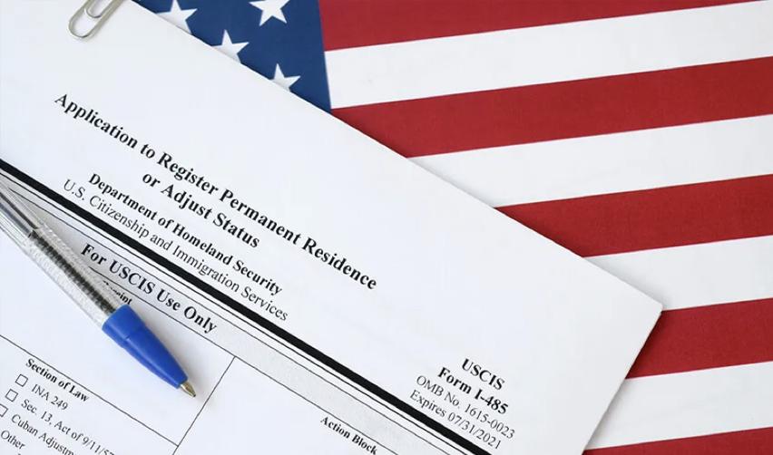 Close-up of a Form I-485, Application to Register Permanent Residence or Adjust Status, on top of an American flag.