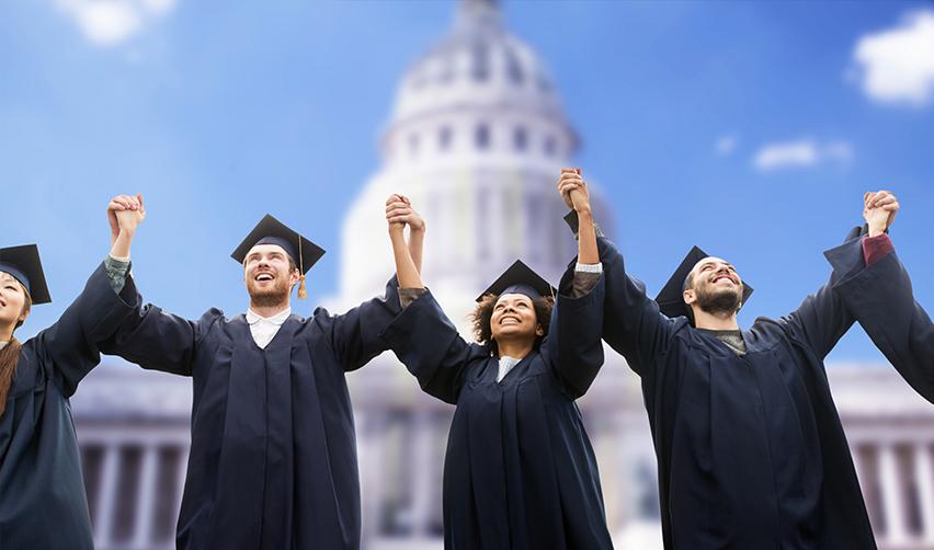 A group of graduates holding hands in front of a U.S. governmental building.