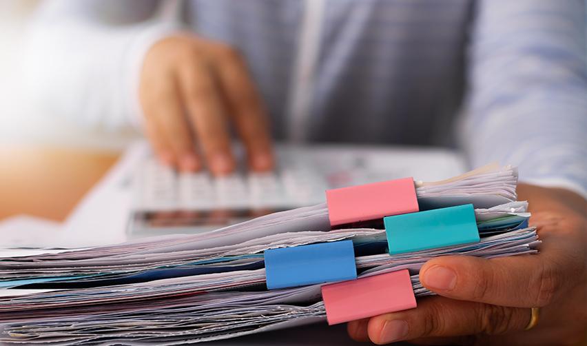 A person holding a stack of supporting documents.