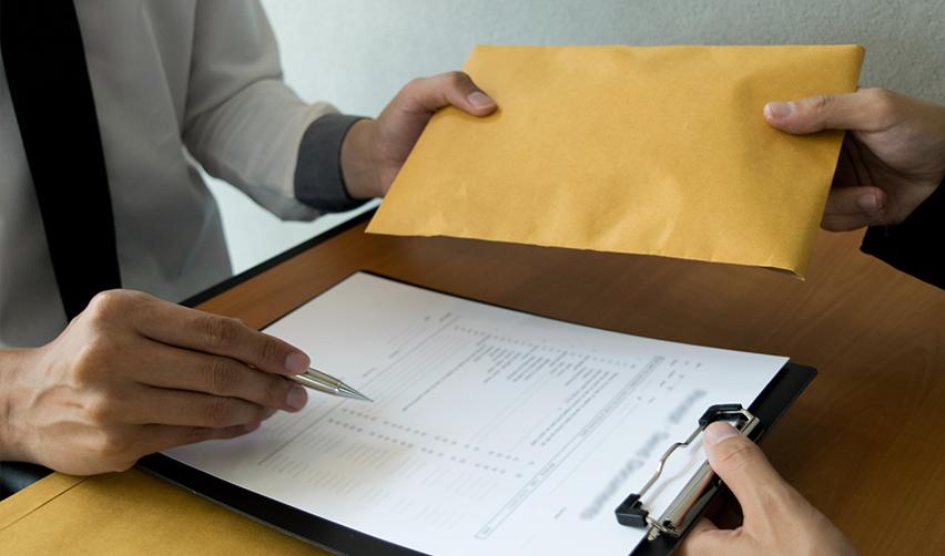 A person holding a envelope and pen while examining some visa documents.