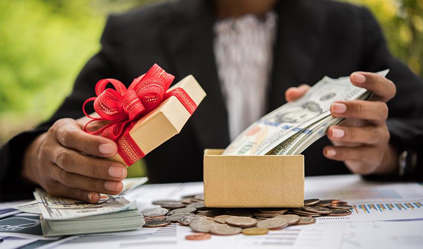 A person holding a gift box with money in it, symbolizing gifts as a source of EB-5 funds.