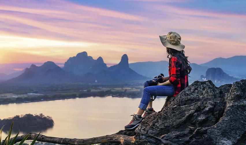A person with a camera on a mountaintop, looking at the view.