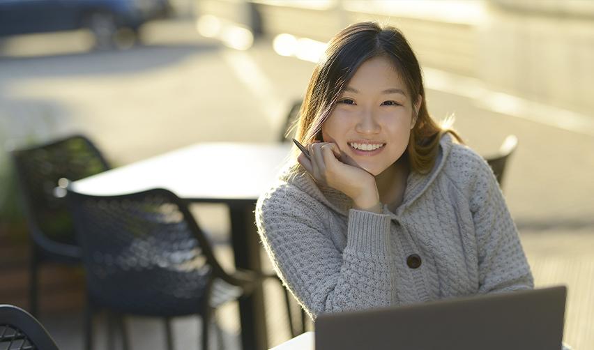 An F1 visa holder sitting in front of a computer with a pen in her hand.