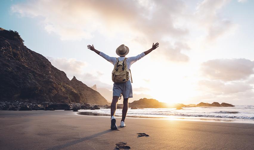 A person with his arms outstretched on a beach, concept of travel and freedom thanks to the advance parole document.