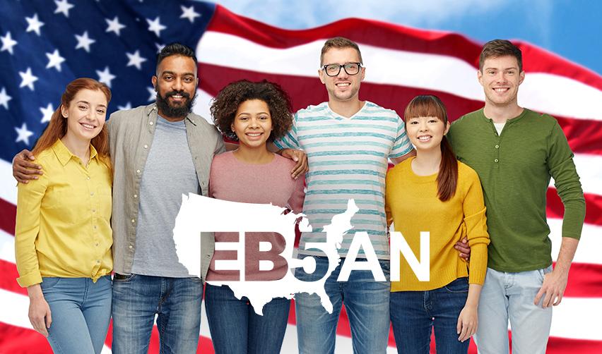 A group of people posing for a photo with an American flag behind them and the EB5AN logo in the foreground.