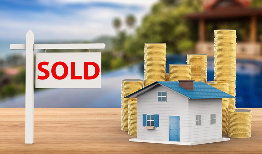 A house model with stacks of coins and a sign that reads