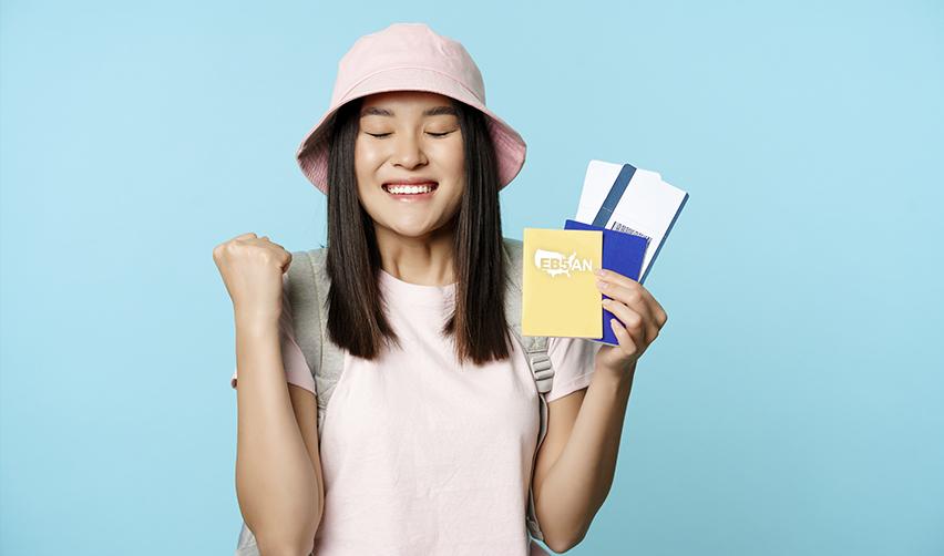 A happy international student who transitioned from F-1 to EB-5, holding boarding passes and a passport with the EB5AN logo on it.