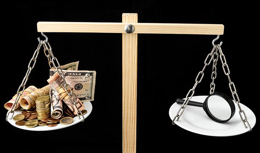 Investment funds representing the EB5 minimum investment amount and a magnifying glass on either side of a wooden scale.
