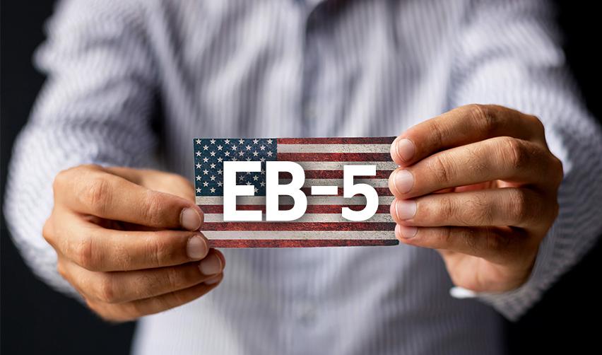 A person holding a small American flag with the word EB-5 on it.