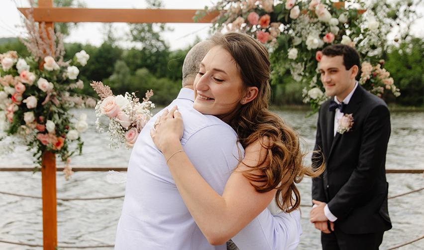 A person hugging a bride at a wedding ceremony.