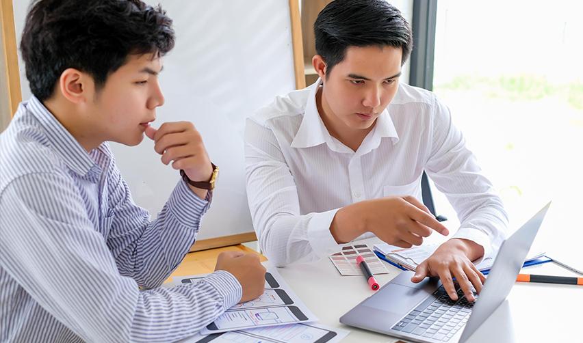 Foreign investors examining some sources on a laptop regarding investment capital or securities laws.