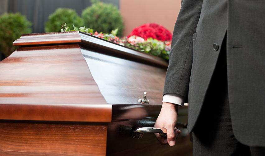 A person in a suit carrying a coffin, explaining what happens when an eb5 investor dies.