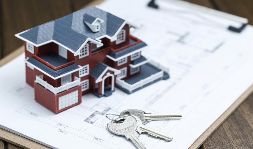 A model house placed on an EB5 project plan with keys next to it.