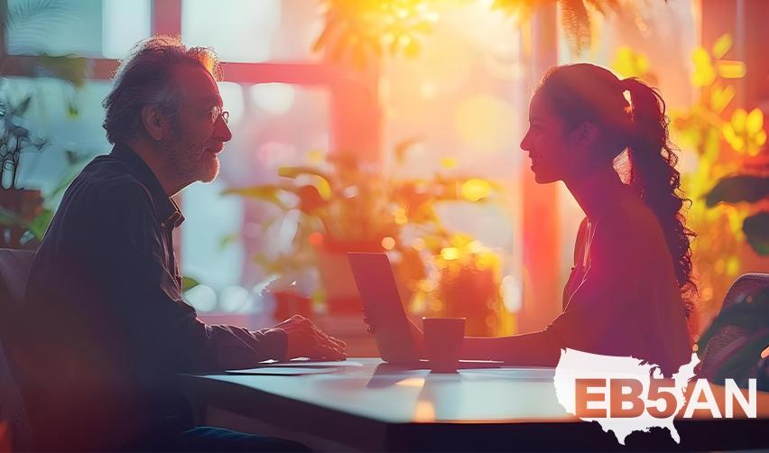 An EB5 investor and a regional center representative sitting at a desk, with the EB5AN logo on the corner.