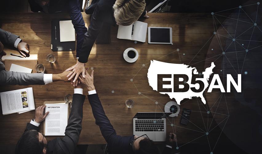 An EB5 regional center team working with alien entrepreneurs at an office desk next to the EB5AN logo.
