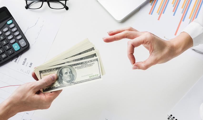 A hand extending investment money to another hand making the