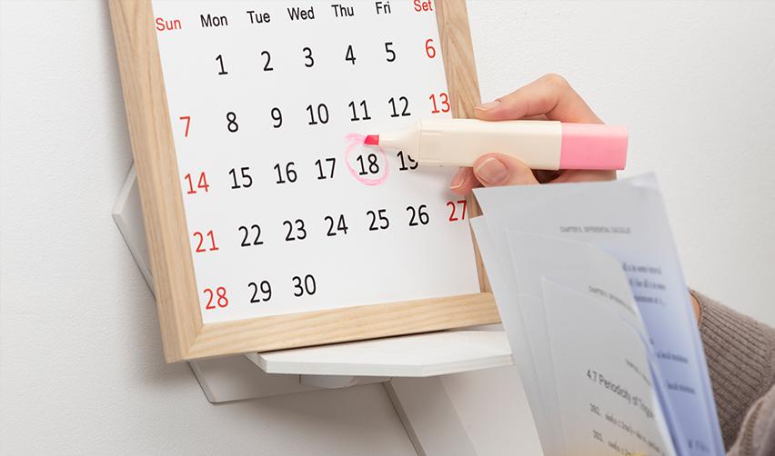 A hand marking a calendar with a highlighter, circling the applicant's priority date.
