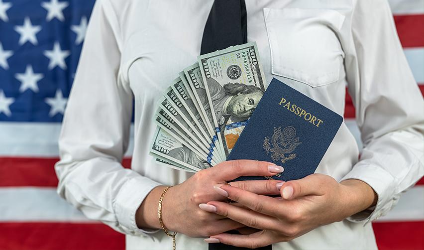 An EB5 investor holding an American passport with investment funds in it.