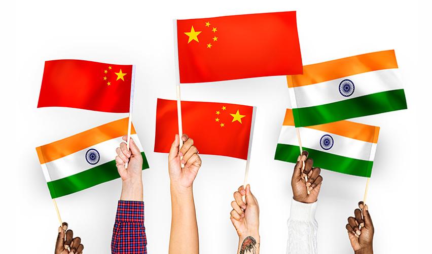 Hands holding up Indian and Chinese flags, symbolizing the final action dates for employment based adjustment of status into permanent residence from high demand countries.