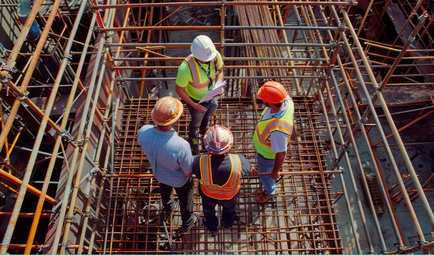 A group of engineers in hard hats working on an EB5 real estate development project site.