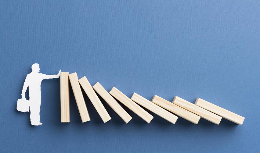 A silhouette of an EB5 investor stopping falling dominoes, symbolizing risk mitigation in EB5 regional center investments.