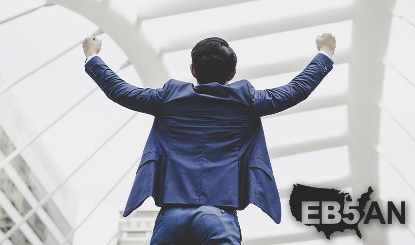 AN EB5 investors celebrating his lawful permanent residency with his arms in the air, with the EB5AN logo on the corner.