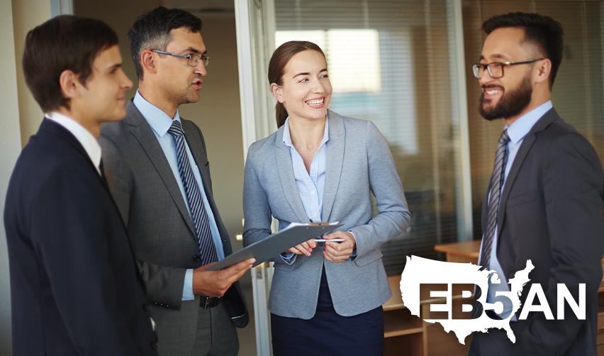 A group of EB5 industry professionals talking to an alien entrepreneur, with the EB5AN logo on the corner.