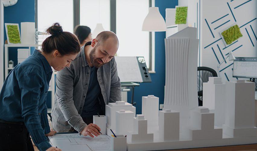 A person and person looking at a model of buildings