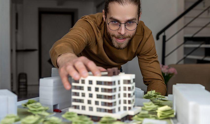A person holding a model of a building